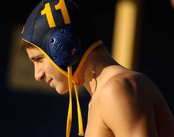 Water polo player wearing a numbered cap looks downward in profile.