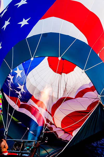 Flames inflate a red, white, and blue hot-air balloon from within.