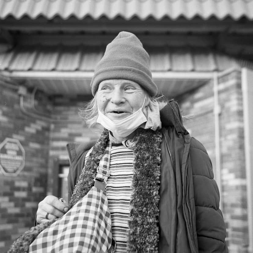 Person in winter clothing carries a checkered bag with a mask lowered.